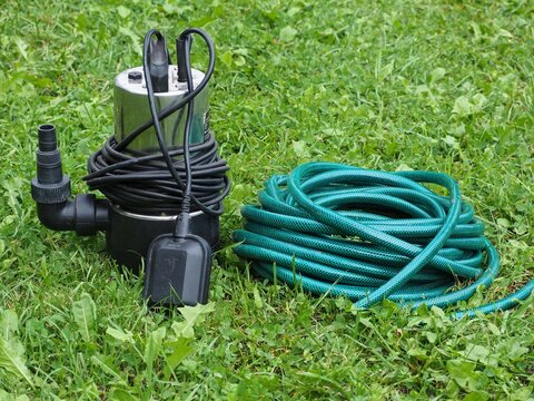 Clean and dirty water pump with green hose. Black submersible water pump with water level gauge