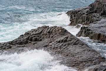 rocky seashore formed by columnar basalt against the stormy sea, coastal landscape of the Kuril...