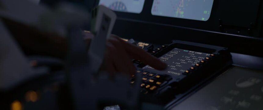 CU Commercial aircraft pilot adjusting flight parameters of the plane during the flight at high altitude. View from inside the cabin. Real aircraft, nighttime shot