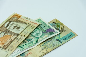 Collection of Saudi Arabia and Oman and Qatar riyal banknotes on a white background. Selective focus.