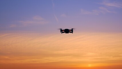 A drone flies in the sunset sky and glows with its light bulbs. A futuristic future where drones...