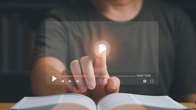 Businessman Or Student Playing The Video For Learning New Technology Or Music. Finger Pointing At Play Button On Virtual Screen And A Book Is On The Table. Studying Or Learning Concept.