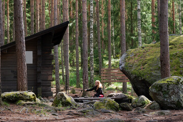 Woman sitting on the Sorsakolu campfire site in the Evo hiking area, Hameenlinna, Finland