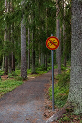 No biking sign next to a hiking trail in a pine forest in summer