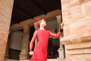 Portrait of young teenage woman in red dance suit with ruffles and red carnations in her hair doing...