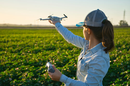 Farmer Woman Checks The Field With Dron. Inteligent Agriculture And Digital Agriculture Transformation