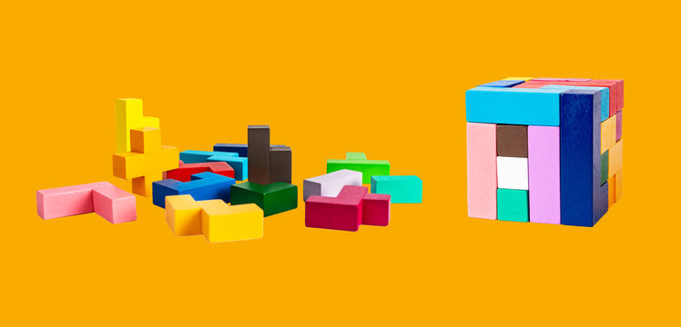 Wooden puzzle pieces and cube on orange background. Chaos and order or construction, building concept. Toy for children