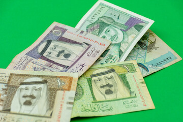 Collection of Saudi Arabia riyal banknotes on a green background. Selective focus.