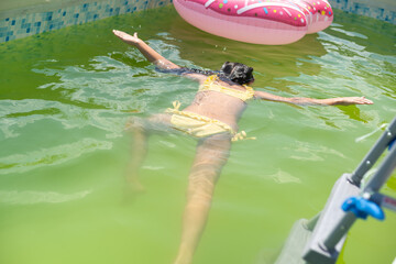 little girl in the green water of very dirty pool