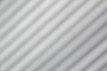 Diagonal blinds shadow on a white plastered wall, black and white style backdrop