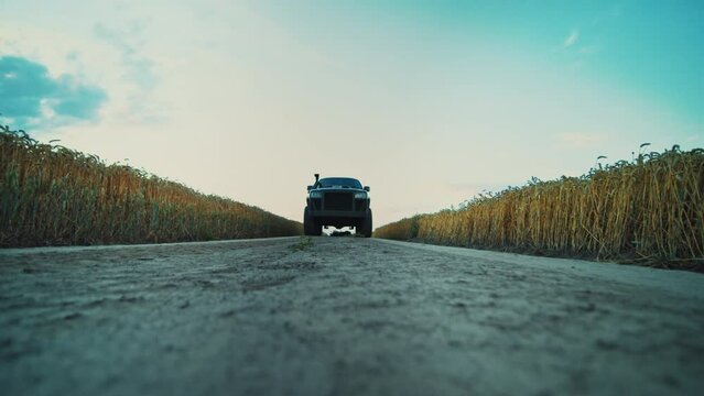 On trail moving car. On background dusty dirt road near wheat field. The car goes off-road. Automobile. Transportation. Vehicle. Slow motion