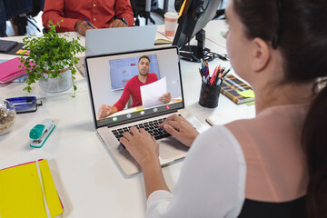 Caucasian woman planning with male coworker on videocall over laptop at office