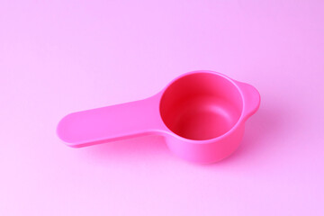 Colorful plastic measuring spoons and measuring cups on bright background