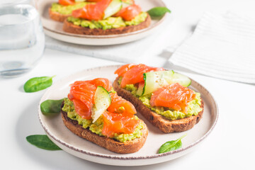 Open sandwich with smoked and salted salmon for healthy breakfast. Trout and avocado on bruschetta toast. 