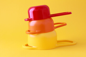 Colorful plastic measuring spoons and measuring cups on bright background