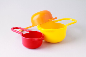 Colorful plastic measuring spoons and measuring cups on bright background