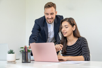 Businessman mentor advising sharing ideas with female businesswoman colleagues using laptop sitting...