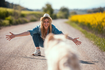 Attractive young woman caring and playing with her beautiful golden retriever dog in a rapessed...