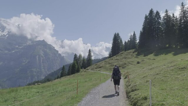 Man with backpack trekking in Swiss alps, Murren Lauterbrunnen Region. 4k video 29.97 fps(Panasonic S1 Vlog, Apple ProRes422HQ)