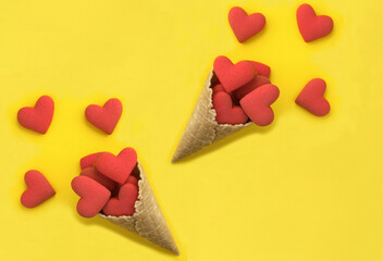 Obraz na płótnie Canvas Ice cream cone with red heart shaped cookies on the yellow background. Top view. Copy space.