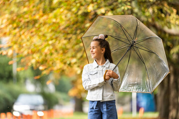 Obraz premium Kid playing out in the rain. Children with umbrella play outdoors in rain. autumn weather.