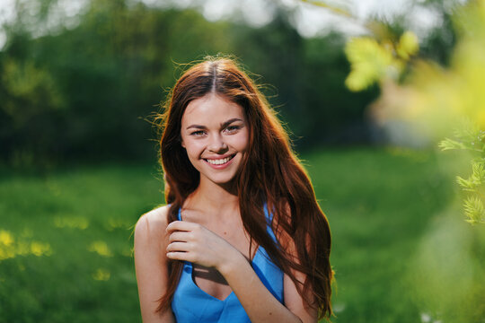 Portrait of a young woman with a beautiful smile in nature on a background of greenery in the spring on a sunny day, the beauty of health and youth, happiness
