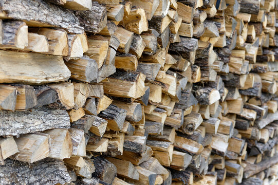 Dry chopped firewood logs, wooden pile texture. Log background. View of a stack of firewood.
