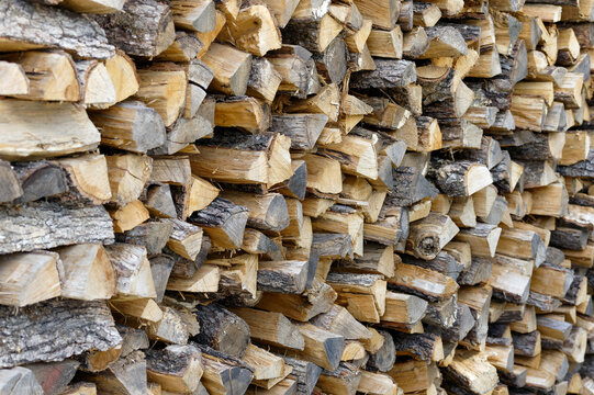 Dry chopped firewood logs, wooden pile texture. Log background. View of a stack of firewood.
