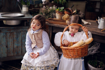 Two little girls sitting on terrace with basket of bread and buns. Little baby sisters of 3 and 5...