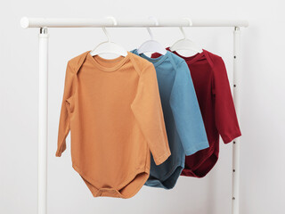 Multicolored long sleeve baby bodysuits hanging on a hanger