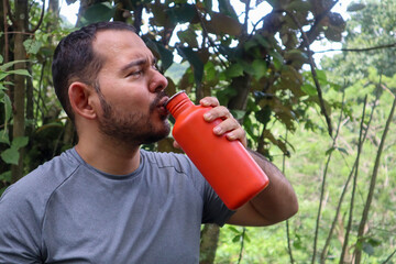 Sporty young man drinking from an orange bottle 