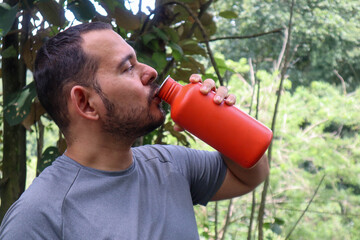 Sporty young man drinking from an orange bottle 