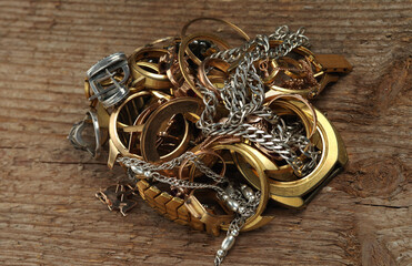 Old and broken jewelry, watches of gold and silver on a wooden texture. A scrap of gold.