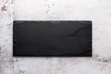 Empty black slate board on light damage concrete background.