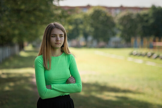 Portrait of a young beautiful girl in a green blouse and black parka pants.
