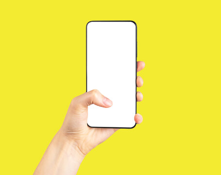Hand holding phone mockup and clicking or swiping on yellow background. Woman using smartphone for surfing Internet, social media. Telephone template with white screen