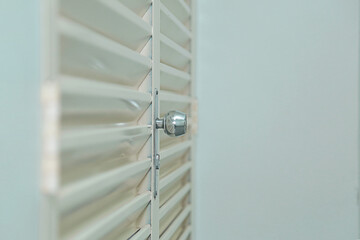 Uma porta de aço laminada, fechada, na cor creme com maçaneta prateada.