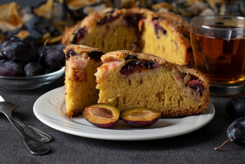 Homemade open pie with plums and cup of tea on gray background, Close-up