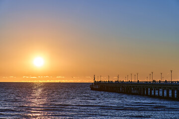 Obraz premium Orange sunset in the sea near a wooden pier