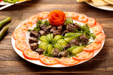 Grilled liver with salad served in a dish isolated on wooden table background side view of fastfood