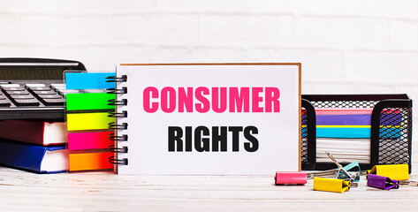 On a light wooden background, a calculator, multi-colored sticks and a notebook with the text...