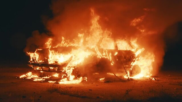 Dark on street shot of burning car in the city. Orange fired. Automobile engulfed in flames of fire. Explosion. Bomb. Car crash. Burning wheel. Emergency