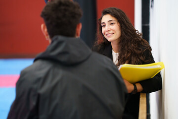 Friendly female counselor listening to sportsman in gym