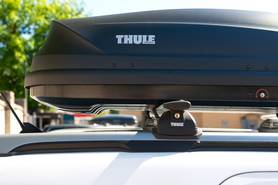 Saint-Petersburg, Russia-June 25, 2022: Thule luggage box on the roof of white car. The car is ready for a long journey. A convenient and roomy box for storing travel bags on the roof of the car.