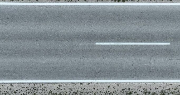 Aerial Top View of an asphalt road with markings. Passing car view from a height. Tracking shoot.