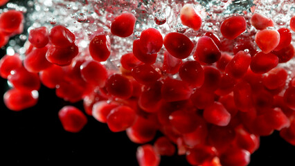 Sweet pomegranate seeds splashing underwater. Fresh pomegranate background with copy space for your text. Vegan and vegetarian concept.