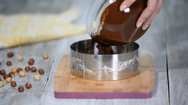 Close-up of the chocolatier's hands pouring chocolate into confectionery ring.