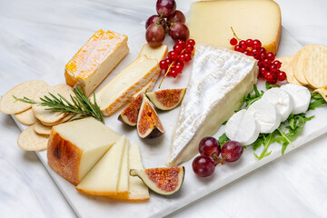 Cheese plate with pecorino brie goat cheese with crackers breadsticks figs jam olives and berries	