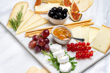 Cheese plate with pecorino brie goat cheese with crackers breadsticks figs jam olives and berries	