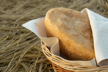 wheat and bread on the field in a wicker basket, natural colors, organic bread, in the rays of the setting sun, at sunset